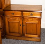 An Oak Two Drawer Cupboard with scratch carving to the dorr and brass drop handles. 40 inches high