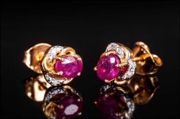 Pair of Ruby Stud Earrings with diamond accents, the oval cut rubies, of good colour, set in a frame