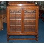 A 1930's Double Glazed Door Oak Display Cabinet On Turned Legs with a cross stretcher. 41'' in