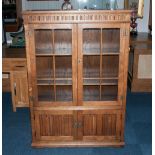 A Golden Oak Double Door Glazed Display Cabinet with the mock jacobean style with 2 linen fold