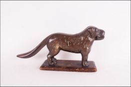 A Late 19th Century Cast Iron Novelty Nut Cracker In The Form of a Long Tailed Dog, Supported on