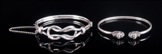 Two Various Silver Bangles, one with an interlocking double loop design, hinged, with tongue and box