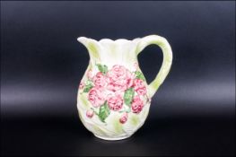 What's Pottery Jug with embossed green and pink floral decoration. 8 inches in height.