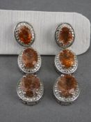 Tanzanian Sunstone Triple Drop Earrings, each earring having three graduated oval cut sunstones, a