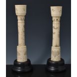 Two very similar Japanese segmented bone candlesticks, both with ebonised bases.