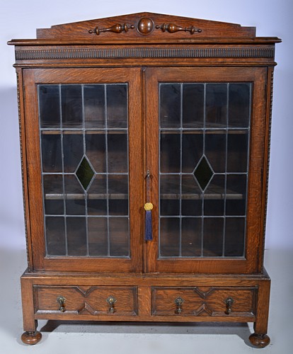Oak bookcase, raised back, two leaded glazed doors enclosing shelves, with two drawers under,