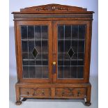 Oak bookcase, raised back, two leaded glazed doors enclosing shelves, with two drawers under,