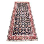 A large antique Caucasian rug, the field with floral motifs on a deep blue ground,