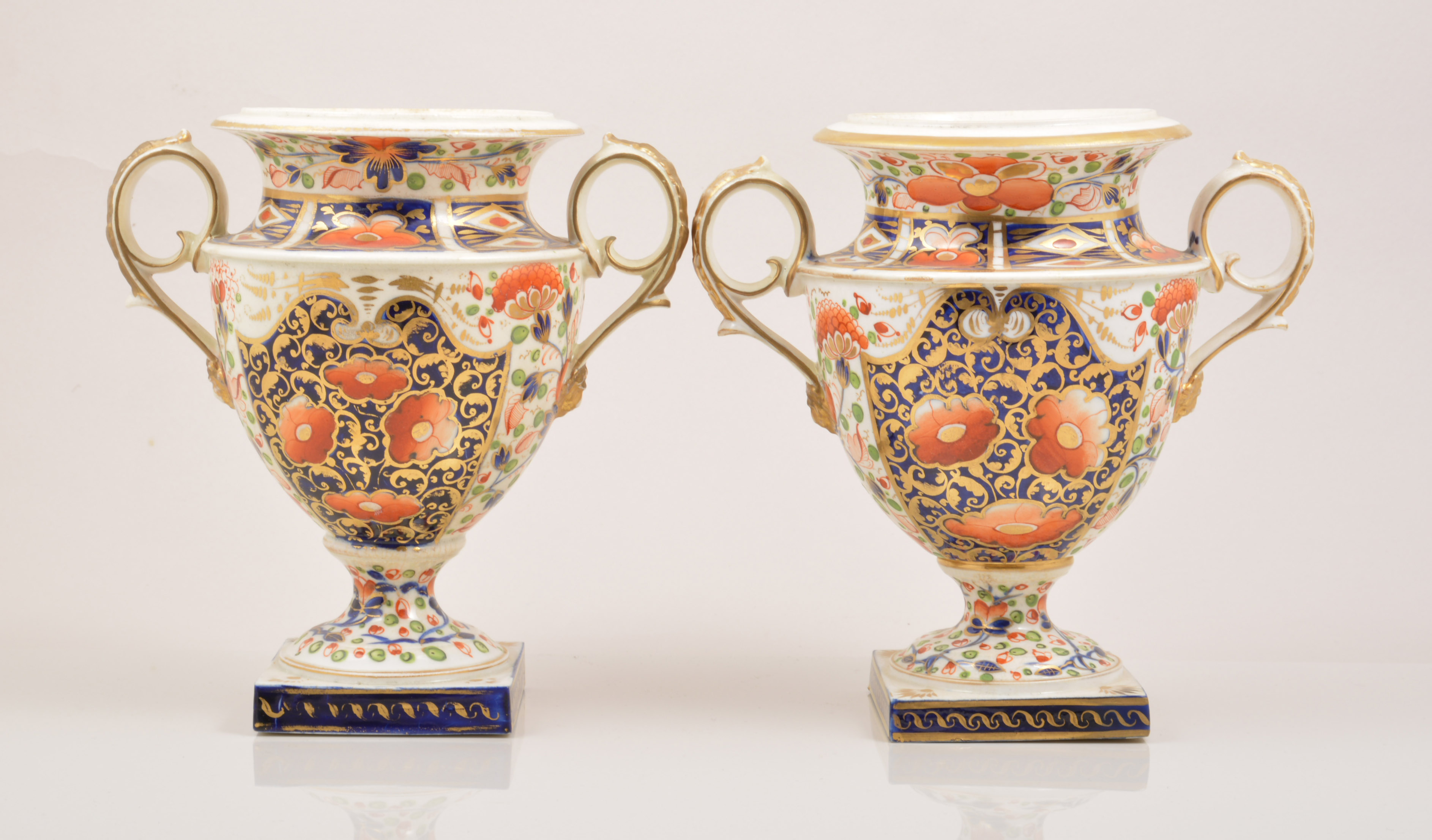 A pair of Derby porcelain campana shaped urns, early 19th Century, each with twin scrolled handles,