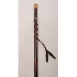 A tortoiseshell walking cane, yellow metal pommel with chased repousse band and engraving, 88cm.