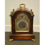 An oak bracket clock, arched top with gilt metal urn finials,