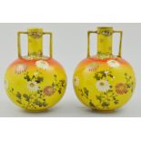 Pair of Japanese Satsuma twin handled vases, decorated with Oriental flowers on a yellow ground,