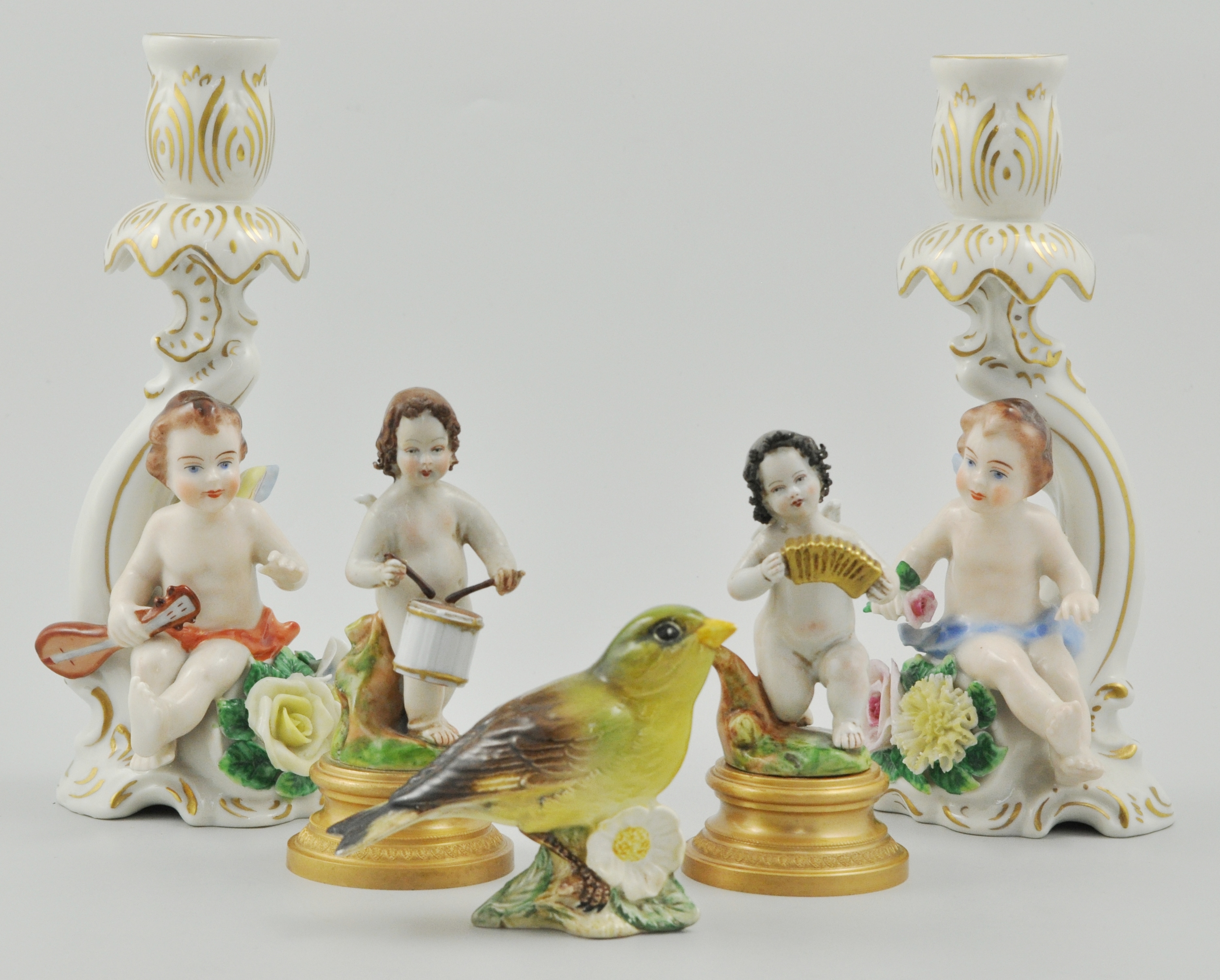 Pair of Sitzendorf candlesticks, decorated with cherubs with flowering encrusted bases,