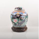 Chinese Famille Noir ginger jar, decorated with peacocks and flowers on a wooden stand,