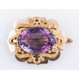 An amethyst yellow metal brooch claw set with an oval mixed cut amethyst 33mm x 23mm in a plain