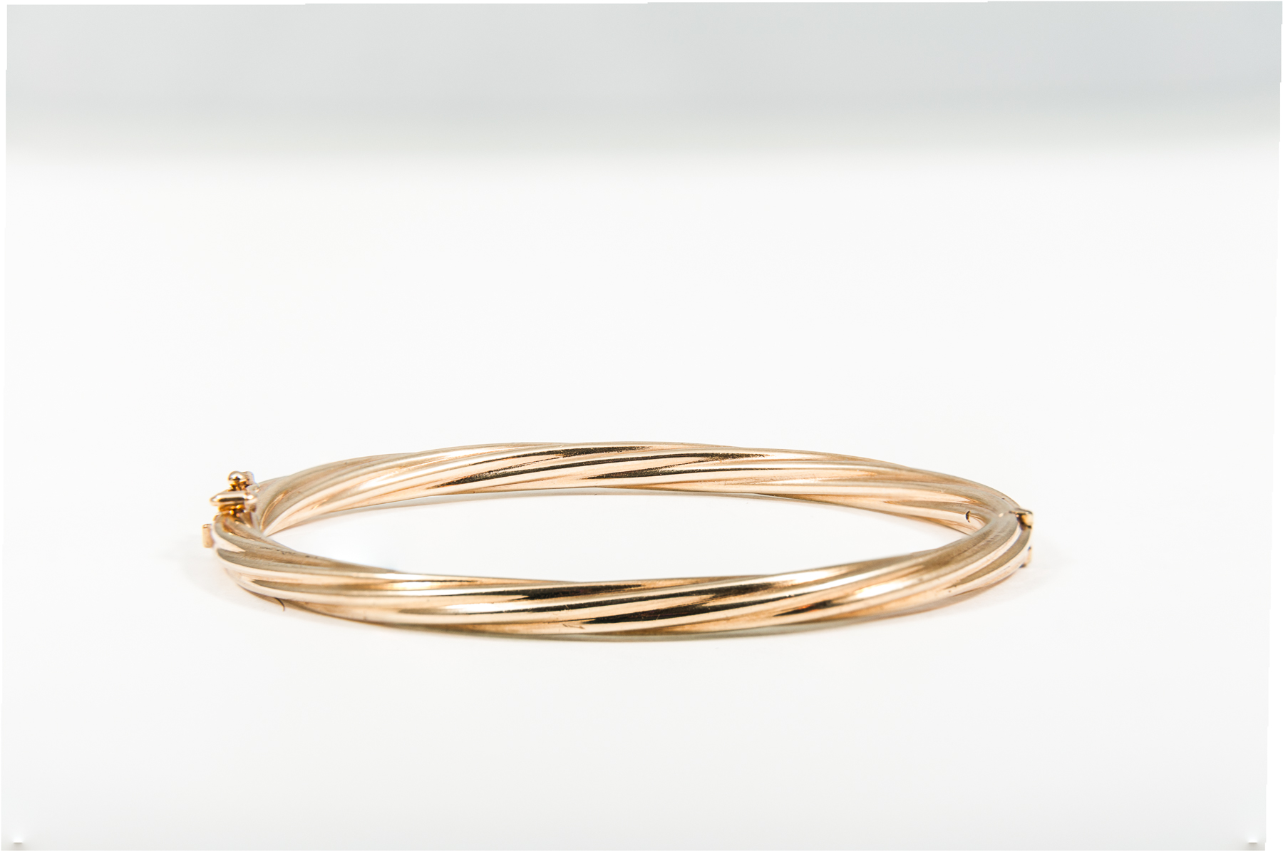 A contemporary hallmarked 9 carat yellow gold bangle of a hollow twisted design,