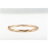 A contemporary hallmarked 9 carat yellow gold bangle of a hollow twisted design,