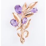 A hallmarked 9 carat yellow polished leaf spray brooch, claw set with four oval mixed cut amethyst.