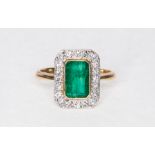 An emerald and diamond rectangular cluster ring, the rectangular mixed cut emerald 7.7mm x 5.