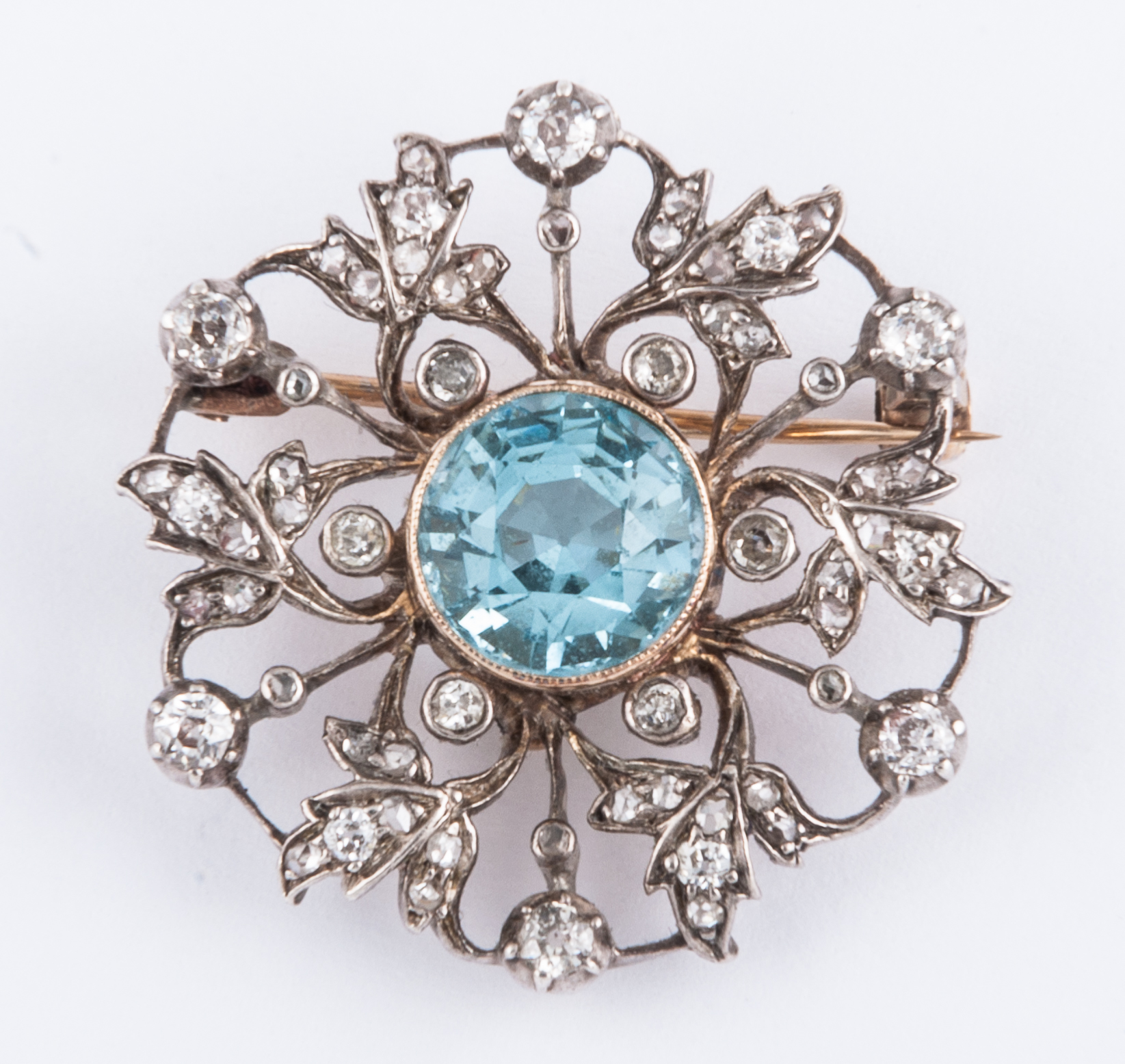 A diamond and aquamarine yellow and white metal circular brooch,