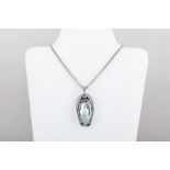 An oval mother of pearl shell pendant with black onyx back in a white metal setting with applied