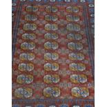 Bokhara rug, with three rows of guls on a red field, border within guards, 80cm x 126cm.