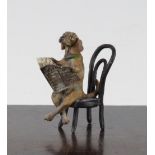 A miniature cold painted bronze model of a seated Dachshund reading a newspaper, in the manner of
