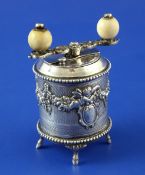 An ornate 19th century French silver drum shaped peppermill, decorated with cherubs and swags and