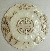 A Chinese pale celadon jade disc, the centre pierced with a shou medallion, withing a border of