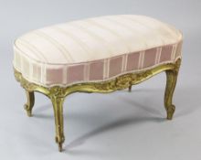 A Louis XV style carved giltwood oval foot stool, with pink stripe overstuffed fabric, with floral