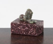 A small Roman bronze figure of a recumbent lion, c.2nd century AD, 3.5cm, together with a porphyry