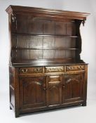 An 18th century oak dresser, with canopied plate rack, shaped sides and two fitted shelves, over