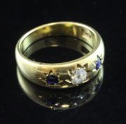 An early 20th century 18ct gold three stone sapphire and diamond gypsy set ring, size N.