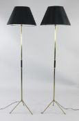 A pair of 20th century tubular brass standard lamps, with spreading tripod feet and black shades,