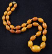 A single strand graduated amber bead necklace, with pierced gilt metal clasp, gross weight 27 grams,