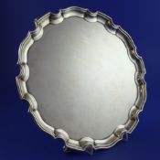 A George V silver salver, of shaped circular form, with pie crust border, on scroll feet, Adie