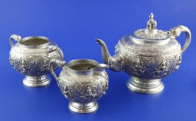 An early 20th century Indian silver three piece tea set, of circular form, embossed with panels of