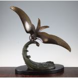 A French Art Deco patinated metal model of a sea bird on the crest of a wave, on oval polished