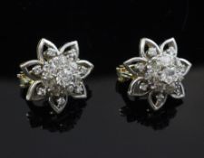 A pair of gold and diamond cluster ear clips, of flowerhead design with diamond set petal borders,