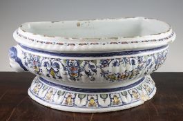 A Rouen faience pottery cistern, c.1720-1740, of reeded semi-circular form with female mask handles,