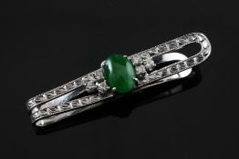 A cabochon jade and diamond set clip, the white metal setting with bright cut engraved decoration