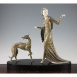 A French Art Deco patinated metal and ivorine figure group, of a lady and dog, on oval black