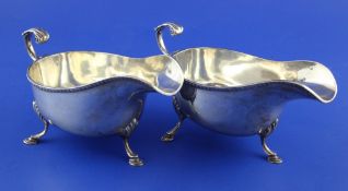 A pair of Edwardian Irish silver sauceboats, with flying scroll handles and gadrooned border, on