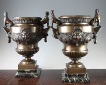 A pair of French Egyptian revival bronze urns, the lion mask handles mounted with sphinx, the