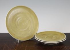 Dame Lucie Rie. A mustard glazed pottery plate and two matching saucers, each with a typical