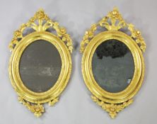 A pair of 19th century gilt oval wall mirrors, with pierced floral crests, 2ft 5.5in. x 1ft 5.5in.