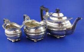 An Edwardian three piece silver tea set, of oval form, with fluted band and shell and gadrooned