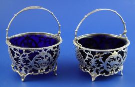 A matched pair of early 20th century silver tub shaped sugar baskets, with blue glass liners and