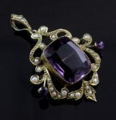 An Edwardian 9ct gold, amethyst and seed pearl set drop pendant brooch, of openwork scroll design,