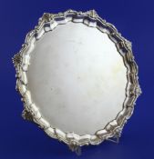 A 1930's silver salver, of shaped circular form, with shell and scroll border, on scroll feet,